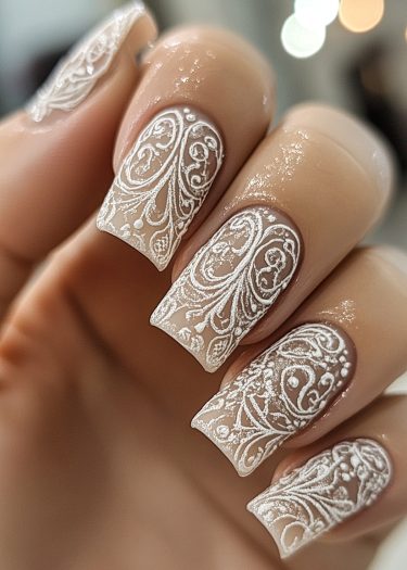 Elegant nude nails with intricate white lace design and glossy finish for stunning nail art.