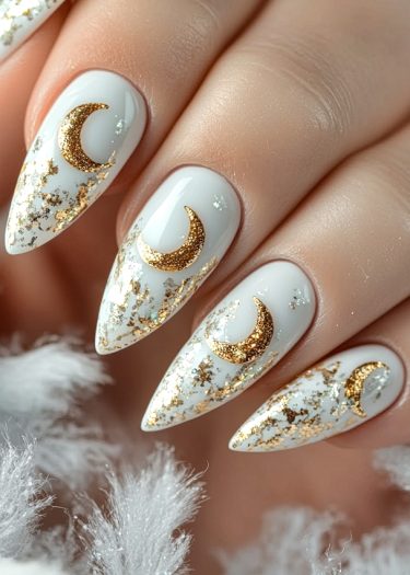 Elegant stiletto nails featuring glossy white polish, gold foil accents, and celestial moon designs.