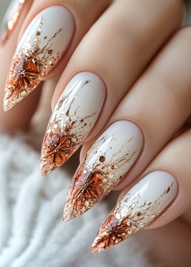 Elegant stiletto nail art featuring intricate gold foil and floral designs on nude base.