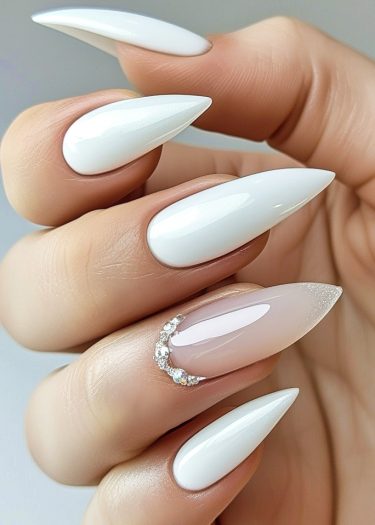 Elegant stiletto nails featuring glossy white polish and sparkling rhinestones for a chic manicure.