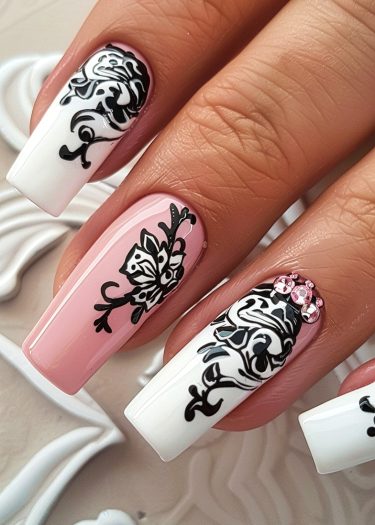 Elegant floral black nail art with pink accents and rhinestones for a chic manicure.