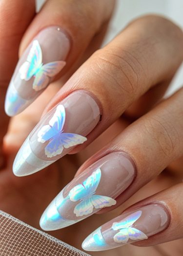 Elegant manicure with iridescent butterfly decals on almond-shaped nails in soft nude polish.