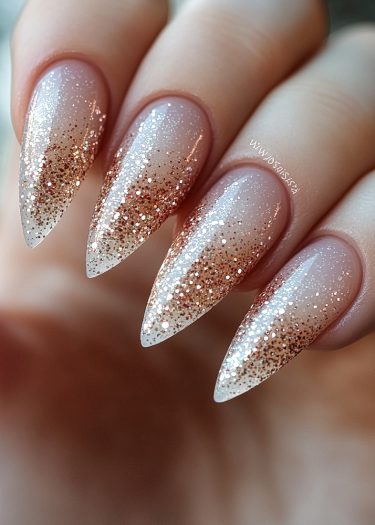 Elegant stiletto nails featuring nude ombre and sparkling glitter for sophisticated nail art.