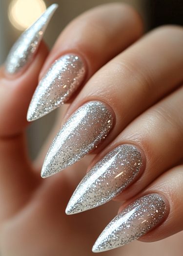 Glamorous silver glitter stiletto nails shine brightly against a blurred neutral background.