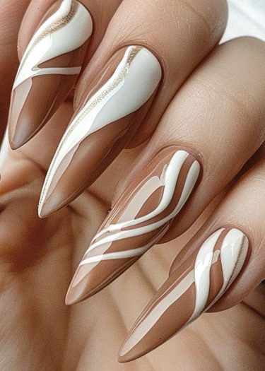 Elegant stiletto nail art in muted nudes and shimmering gold and white designs.