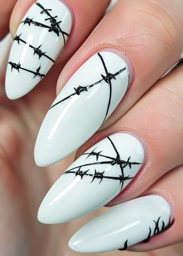 Almond-shaped white nails featuring intricate black barbed wire art for a bold fashion statement.