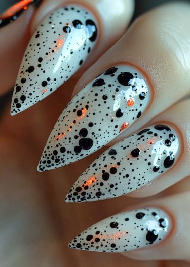 Stunning white and black speckled stiletto nails with shimmering orange accents for a bold look.