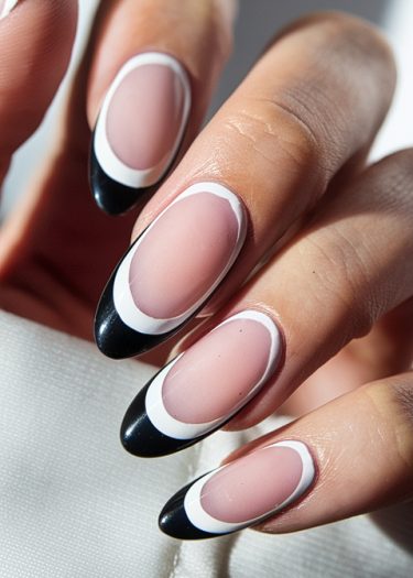 Stylish almond-shaped nails featuring a modern black and white French tip design.