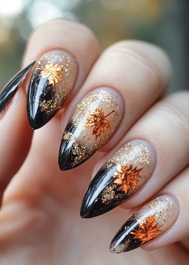 Gorgeous autumn leaf nail art with gradient black tips and sparkling gold details.