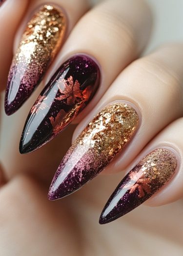 Elegant autumn stiletto nails featuring burgundy, gold, and floral designs with glitter accents.