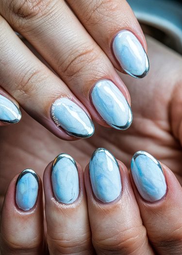 Elegant baby blue marble nails with metallic silver tips for a chic, modern manicure.