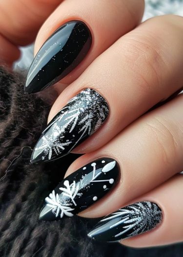 Sophisticated black almond nails with winter-themed nail art and glitter accents.