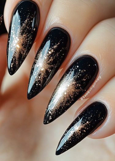 Elegant black and gold stiletto nails with stunning glitter design for a luxurious look.