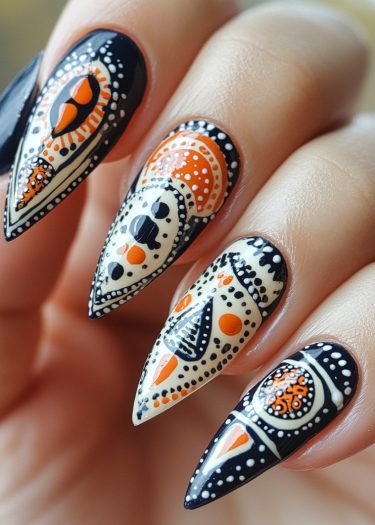 Stiletto black and orange geometric nail designs feature intricate patterns and vibrant contrast.