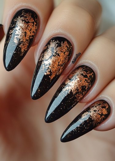 Elegant black stiletto nails with burnt orange foil design and metallic shimmer.