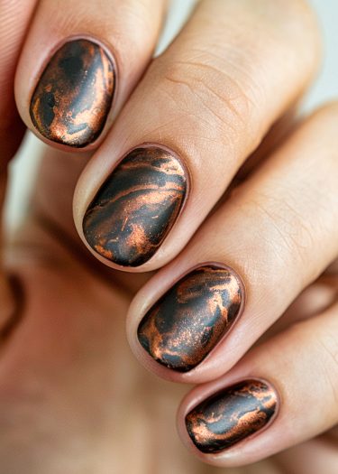 Elegant black and copper marbled nail art with a shimmering metallic effect.