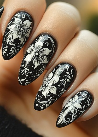 Elegant black and white floral nail art with hibiscus designs on almond-shaped nails.