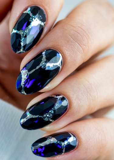 Elegant black glass nail art with holographic accents and silver foil for a stunning look.