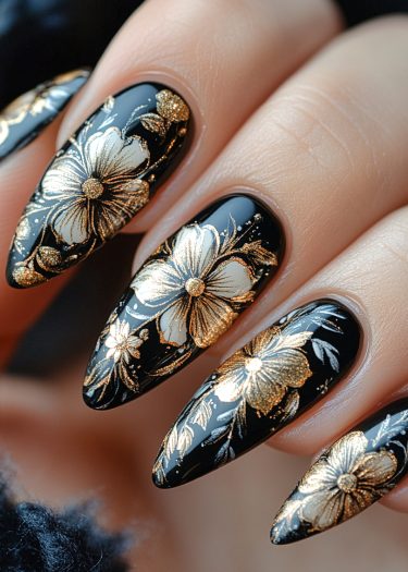 Elegant almond-shaped black nails featuring intricate gold and white floral nail art design.