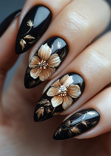 Elegant black and gold floral nail art design with metallic details on almond-shaped nails.