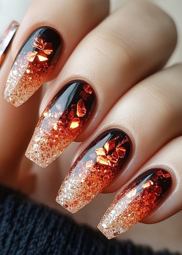 Stunning black and orange ombre coffin nails with crystalline embellishments for glamorous nail art.