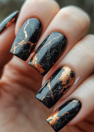 Elegant black and gold marble nail art with a glossy finish.