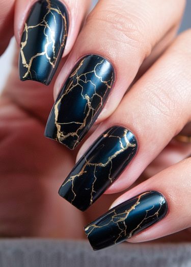 Elegant black and gold marble nail art with intricate designs on beautifully manicured long nails.