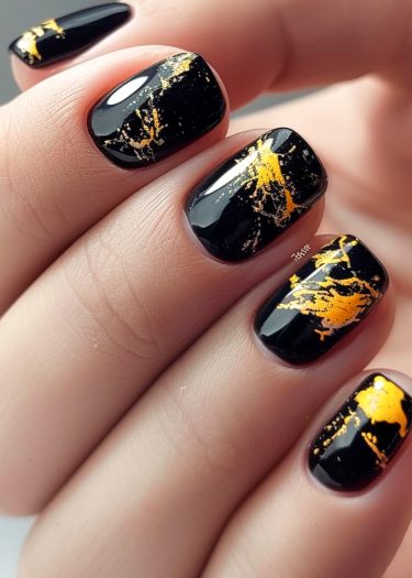 Elegant black and gold nail art featuring glossy finishes and abstract designs.