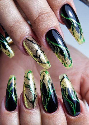 Elegant black and gold nail art with intricate green leaf designs on stiletto-shaped nails.