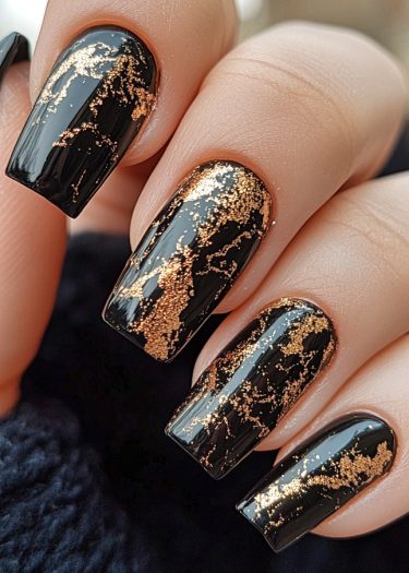 Elegant black and gold nail design with intricate patterns on glossy, manicured nails.