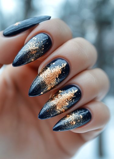 Stunning black stiletto nails with elegant gold glitter design for a chic manicure look.