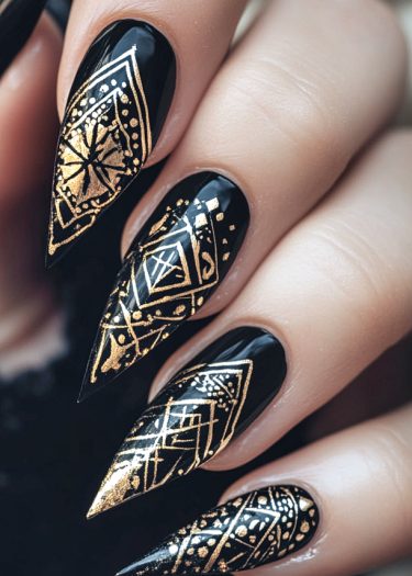 Elegant black stiletto nails with intricate gold geometric designs for a luxurious look.