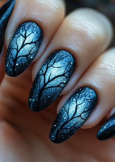 Elegant black almond nail art featuring winter tree branches and shimmering glitter accents.