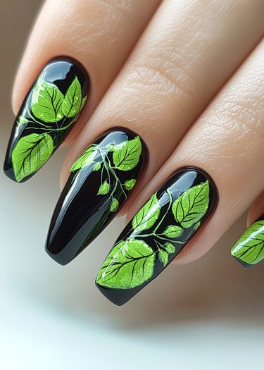 Elegant black nail art featuring vibrant green leaves, showcasing intricate and creative designs.