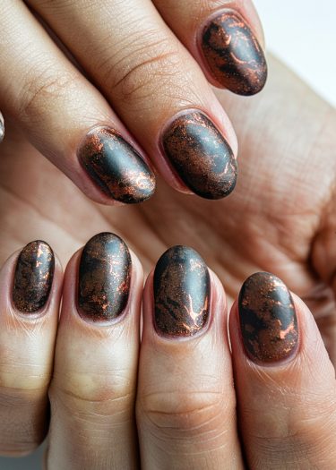 Luxurious black metallic nails with copper marbling for a sophisticated, artistic look.