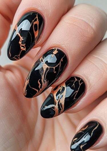 Elegant black almond nails with intricate copper-gold design for a sophisticated manicure.