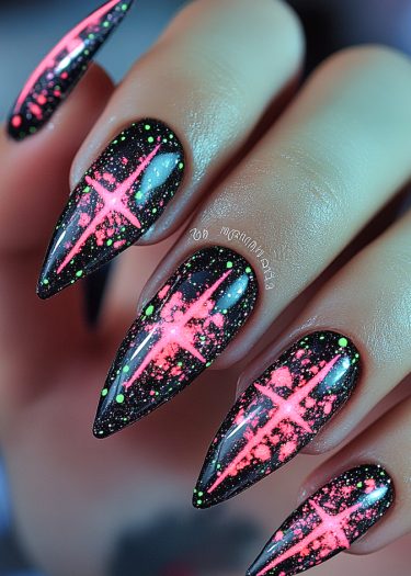 Elegant black stiletto nails featuring neon pink starburst designs and lime green speckles.