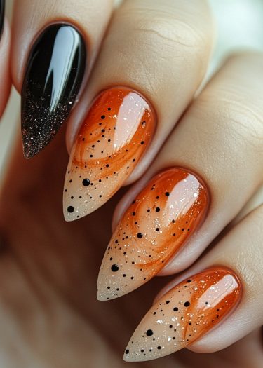 Stunning black and orange gradient stiletto nails featuring intricate patterns and glitter accents.