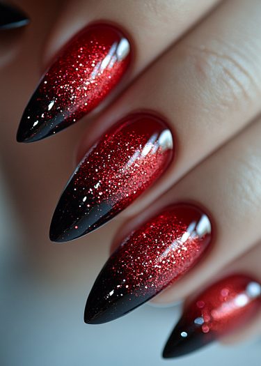 Stunning black and red gradient stiletto nails with glitter for a bold, elegant look.