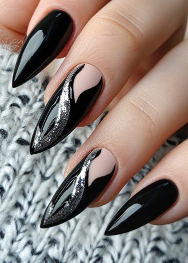 Elegant black stiletto nails with intricate nude design and silver accents for a bold manicure.