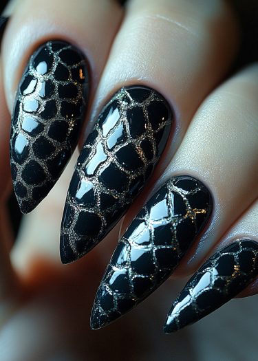 Glamorous black stiletto nails with metallic gold snakeskin pattern for a bold, elegant look.