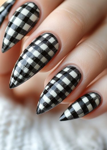 Stiletto nails featuring a striking black and white checkered pattern for bold nail art.