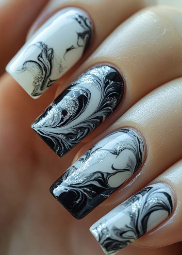 Elegant black and white marbled nail art with silver accents for a sophisticated look.