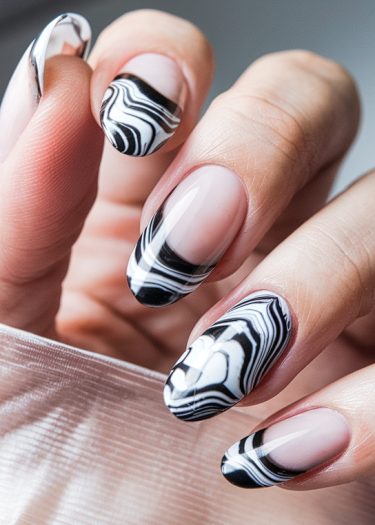 Elegant black and white marble nails in almond shape, showcasing detailed manicured artistry.