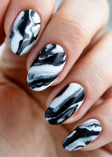 Elegant black and white marble nails with a glossy finish and almond shape for stylish manicures.