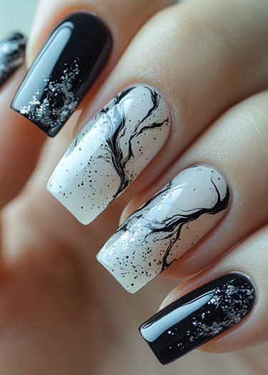 Elegant black and white nail art with glitter and marbled design for a chic look.