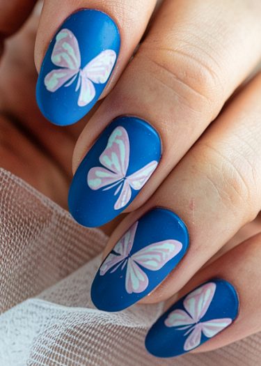 Vibrant blue butterfly nail art with intricate pastel designs on beautifully manicured nails.