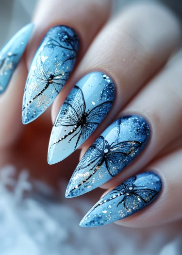 Elegant blue stiletto nails with detailed dragonfly designs and shimmering glitter accents.