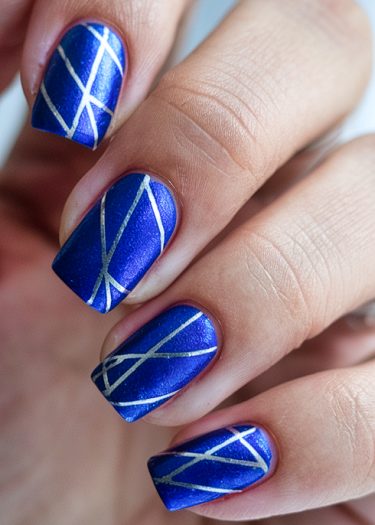 Metallic blue geometric nail art with silver detailing for a stylish, modern look.