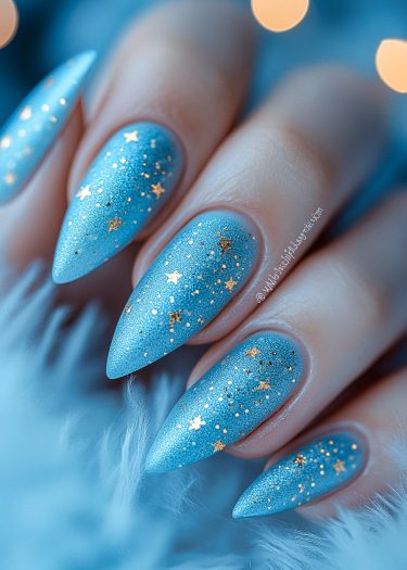 Stunning stiletto blue glitter nails with gold star accents for a cosmic-inspired manicure.